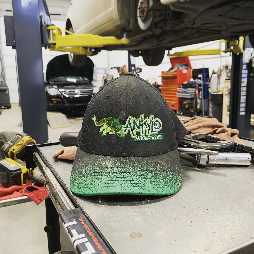 The shop cap on the workbench, a car up on the hoist behind